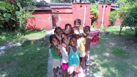 Poor-orphan-little-children-waving-goodbye-to-camera,-slow-motion-shot,-camera-moving-backwards