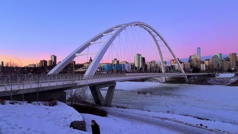 Zeitraffer-Bei-Sonnenuntergang-In-Der-Dämmerung,-4K,-Akzentuiert-Durch-Die-Weiße,-Moderne-Walter-Dale-Brücke-Mit-Einem-Atemberaubenden-Horizont-In-Blau,-Lila,-Rosa,-Orange-Und-Menschen,-Die-Alleine-Gehen-Und-Maskiert-Sind-Und-Zufällig-Andere-Respektieren,-Die-In-Der-Nähe-Gehen