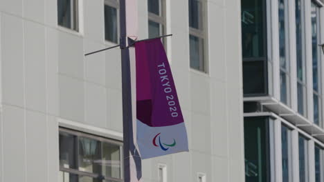 Tokyo-2020-Olympic-Banner-Waving-and-Billowing-In-The-Wind-With-Buildings-In-Background---low-angle-shot