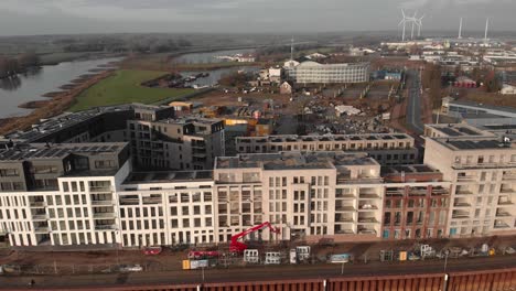 Vista-Aérea-Ascendente-Y-De-Arriba-Hacia-Abajo-Del-Barrio-Noorderhaven-Con-Paneles-Solares-En-La-Parte-Superior-Del-Edificio-Residencial-Y-El-Sitio-De-Construcción-En-El-Fondo-A-Lo-Largo-Del-Lecho-Del-Río-Ijssel