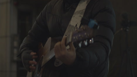 Guitarist-performing-on-the-city-street-at-dark-cold-night