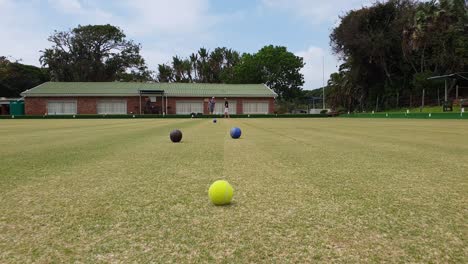 Männer-Spielen-Rasenbowling-An-Einem-Sonnigen,-Ruhigen-Tag-In-Einer-Küstenstadt