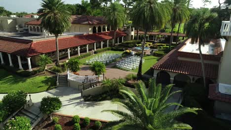 Vista-Aérea-De-Las-Sillas-Que-Se-Preparan-Para-La-Ceremonia-De-Boda-En-Un-Resort-De-Lujo-En-Un-Día-Soleado-En-Florida