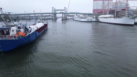 Pre-fabricated-Columns-Loaded-In-A-Cargo-Ship-In-Gota-River---Hisingsbron-Bridge-Construction-In-Gothenburg,-Sweden---low-aerial-drone