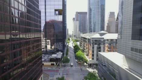 Vista-Aérea-Volando-Sobre-Una-Calle-Y-Entre-Rascacielos-En-El-Soleado-Austin,-Texas,-Estados-Unidos