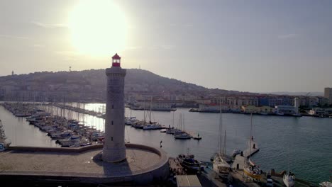 Puerto-Deportivo-Con-Faro-De-San-Louis-Con-Barcos-Detrás-Al-Atardecer,-Toma-Aérea-De-Aproximación-Lenta