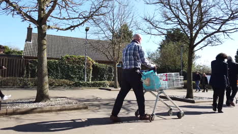 People-pushing-their-trolleys-laden-with-shopping-from-a-supermarket