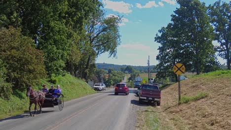 Ein-Amish-Pferd-Und-Ein-Offener-Buggy-Nähern-Sich-An-Einem-Schönen-Sonnigen-Tag-Einer-Landstraße,-Vorbei-An-Autos,-Mit-Amish-Teenagern