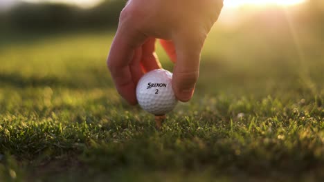 Pelota-De-Golf-Srixon-Preparada-Por-Golfista-En-El-Campo---Primer-Plano-Con-Destello-De-Sol-Al-Atardecer