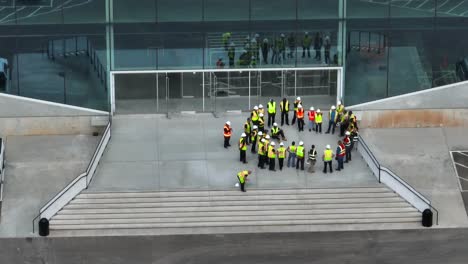 Trabajadores-De-Cuello-Azul-De-La-Construcción-En-Chalecos-Amarillos-Fluorescentes-Se-Reúnen-Como-Equipo-Para-Discutir-La-Gestión-De-Proyectos