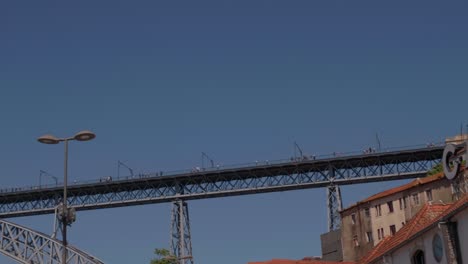 Slow-pan-around-from-port-alcohol-Caves-Calem-famous-signage-across-to-historic-metal-Ponte-Luis-Bridge-structure,-Porto,-Portugal