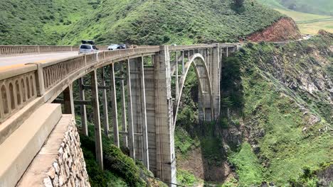 Am-Memorial-Day-Wochenende-Fahren-Autos-über-Die-Bixby-Creek-Bridge-Und-Bieten-Einen-Atemberaubenden-Blick-Auf-Die-üppigen-Grünen-Berge,-Sandstrände-Und-Das-Aquablaue-Wasser-Darunter