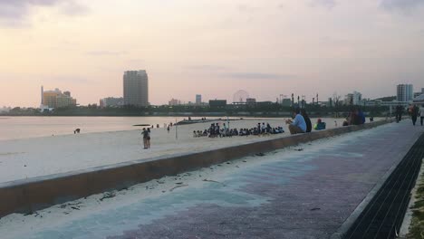 Shot-Panning-Right-of-people-enjoying-the-evening-sunset-at-Araha-Beach,-Chatan,-Okinawa,-Japan