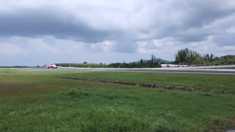 Vista-Panorámica-De-La-Pista-Del-Aeropuerto-Mientras-El-Avión-Airasia-Airbus-A320-Espera-En-La-Pista-En-Un-Día-Nublado--1080-Video-Hd