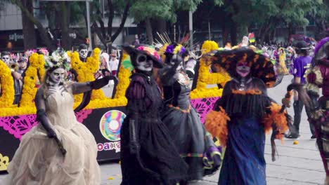 Parade-Zum-Tag-Der-Toten,-Las-Calaveras-Im-Totenkopfkostüm-Und-Ein-Mexikaner-Mit-Sombrero-Tanzen-In-Zeitlupe-Mit-60-Fps