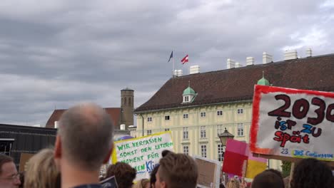 Vista-De-La-Multitud-Sosteniendo-Carteles-Con-El-Telón-De-Fondo-De-La-Bandera-Austriaca-Y-Europea-Durante-Los-Viernes-Para-Futuras-Protestas-Contra-El-Cambio-Climático