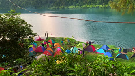 Footage-shot-of-people-setting-up-a-sleeping-tent-by-the-lake-with-a-green-forest-in-the-background