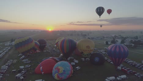 Aerial-View-of-a-Sunrise-Hot-Air-Balloons-Taking-Off-at-a-Balloon-Festival-on-a-Clear-Summer-Morning