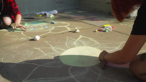 Young-girls-blending-sidewalk-chalk-art-with-their-fingers-during-arts-festival,-Slow-Motion