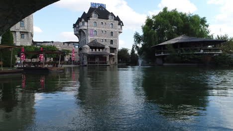 Stanisici-ethnographic-village-hotel-and-resort-low-pull-back-shot-over-water-flying-under-stone-bridge