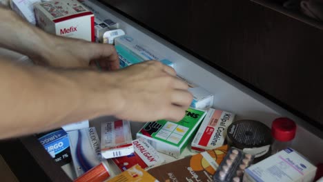 Male-hands-searching-for-medicine-inside-house-drawer,-medium-still-editorial-shot