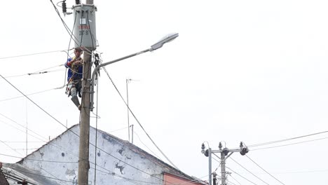 Verschwommener-Und-Geräuschvoller-Clip,-Elektriker,-Lineman,-Reparaturarbeiter-Bei-Kletterarbeiten-Am-Strommast-Des-Strommastes,-Pekalongan