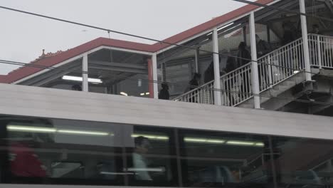 Pendler-Klettern-Auf-Der-Treppe-Am-Bahnhof-Redfern-Auf-Und-Ab,-Im-Vordergrund-Fährt-Der-Zug-Ab---Sydney,-New-South-Wales,-Australien