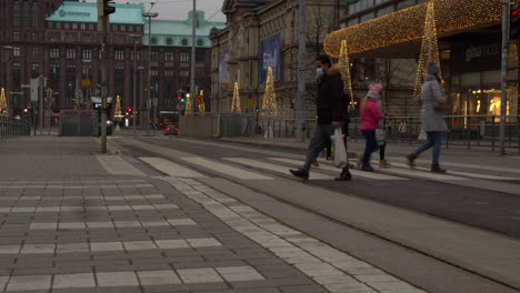 Gente-Cruzando-La-Calle-Entre-La-Estación-Central-De-Trenes-De-Helsinki-Y-El-Centro-Comercial-Decorado-Con-Iluminación-Navideña