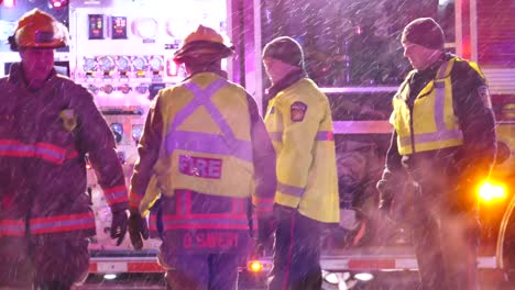 Firefighters-and-police-officers-talking-and-gesticulating-at-the-back-of-a-fire-engine