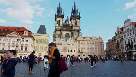 Tourists-and-locals-walking-over-old-town-square-on-a-sunny-day-in-front-of-the-church