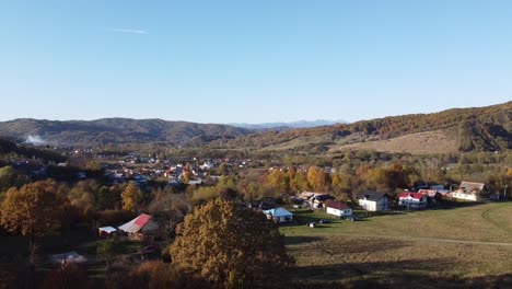 Luftaufnahme-über-Dem-Epischen-Bunten-Herbstwald-Und-Einem-Ländlichen-Dorf-An-Einem-Sonnigen-Tag