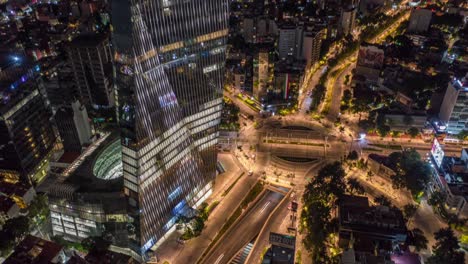 Aerial-Orbit-of-Manacar-Tower-Roundabout-Night-Traffic-in-Mexico-City,-Timelapse-from-above-the-tower