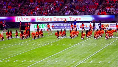 Die-Cheerleader-Der-BC-Stadium-Lions-Felions-Beginnen-Während-Der-Seitenwechselpause-Des-Fußballspiels-Mit-Fröhlichen-Jubelnden-Fans-Auf-Dem-Grünen-Kunstrasen-Im-Innenbereich-Mit-Einem-Sprungtanz-Jubelprogramm