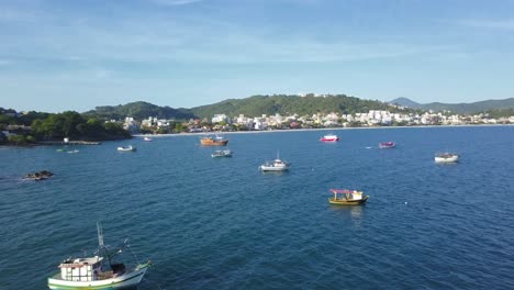 Aerial-shot-flying-over-fishing-boats-working-on-the-sea-near-Bombinhas-beach,-Brazil