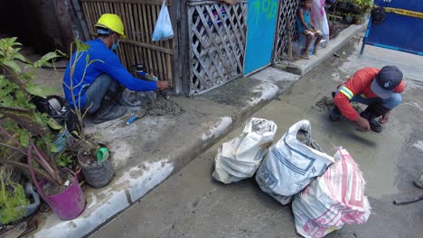 Foremen-wearing-safety-reflective-vests-used-their-shovel,-mixed-cement,-and-demolition-hammer-to-perform-excavation-beside-the-road-gutter-to-install-new-water-piping-from-the-main-water-line