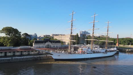 Panorámica-Aérea-A-La-Izquierda-Del-Famoso-Velero-Ara-Libertad-Atracado-En-El-Muelle-De-Puerto-Madero-Durante-El-Día,-Buenos-Aires