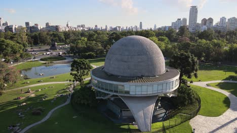 Paneo-Aéreo-A-La-Derecha-Del-Planetario-Galileo-Galilei-En-Los-Bosques-De-Palermo-Con-Edificios-En-El-Fondo-Durante-El-Día,-Buenos-Aires