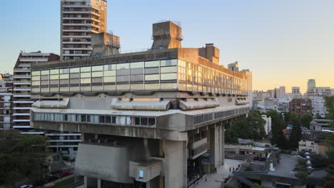 Lufttransportwagen-Aus-Moderner-Nationalbibliothek-Aus-Sichtbeton-Zwischen-Gebäuden-Zur-Goldenen-Stunde,-Buenos-Aires