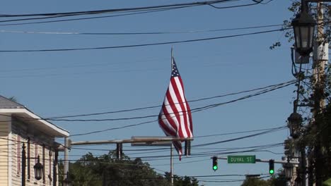 US-flag-in-the-wind-on-famous-Duval-Street-in-Key-West,-Florida,-USA