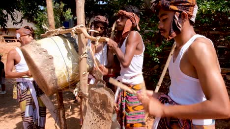 A-group-of-young-boys-playing-a-homemade-drum-to-welcome-visitors-to-their-remote-village-community-in-Timor-Leste,-Southeast-Asia