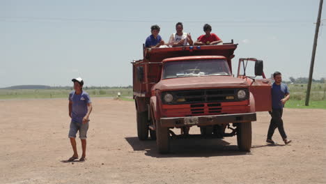 People-in-truck-body,-driver-and-passenger-getting-out-of-truck