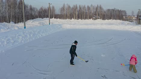 Hombre-Y-Niño-Jugando-Hockey-En-El-Lago-Congelado