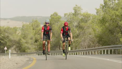 Cámara-Lenta-De-Jóvenes-Profesionales-En-Bicicleta-En-Bicicleta-De-Carretera-Afuera-En-La-Carretera-Del-Desierto