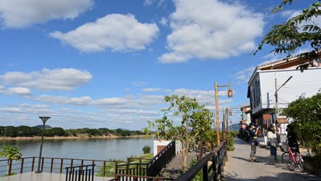 Algunas-Personas-Se-Turnan-Para-Tomar-Fotografías-Mientras-El-Cielo-Es-Azul-Y-Las-Nubes-Se-Mueven-Capturadas-En-Un-Lapso-De-Tiempo,-Calle-Peatonal,-Chiang-Khan,-Loei-En-Tailandia