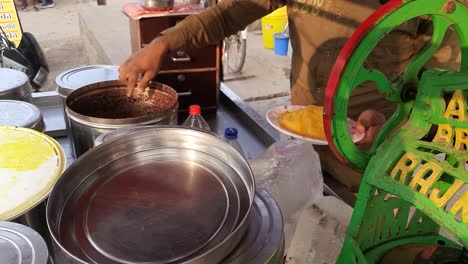 Preparación-De-Chuski:-Un-Hombre-Hace-Paletas-Indias-Famosas-O-Kala-Khatta-Con-Hielo-Picado-Que-Luego-Se-Agrega-Con-Limón-Y-Colorantes-Alimentarios-Aromatizados