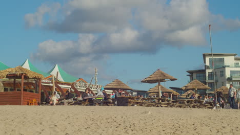 People-Dine-In-On-The-Restaurant-Bar-With-Thatched-Huts-Right-On-The-Beach-In-Perranporth,-UK