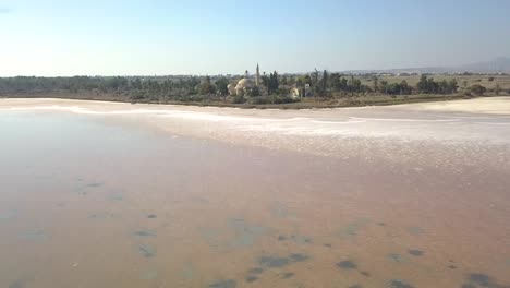 Aerial-Tilt-Shot-Revealing-Historical-Sultan-Hala-Tekke-Mosque-On-Beautiful-Salt-Lake-,-Larnaca-City-,-Cyprus