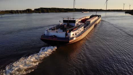 Aerial-Stern-View-Of-FPS-Waal-Inland-Cargo-Vessel-Along-Oude-Maas-With-During-Golden-Hour