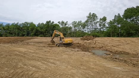 Excavadora-Hidráulica-Deere-Apisonando-La-Suciedad-En-El-Fondo-Del-Estanque-En-Un-Sitio-De-Desarrollo-De-Tierras