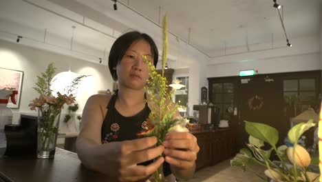 Mujer-Asiática-Con-El-Pelo-Corto-Preparando-Un-Jarrón-De-Flores-En-El-Salón